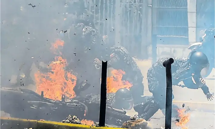  ?? AFP ?? Zona de guerra. Efectivos de la policía huyen del fuego luego de que una bomba molotov estallara contra uno de sus vehículos y provocara su caída. Ocurrió ayer en Caracas.