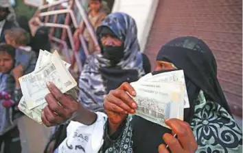  ?? AP ?? Women display currency notes after receiving cash support from Unicef in San’aa. Prime Minister Ahmad Obeid Bin Daghir said saving the Yemeni riyal means “saving Yemenis from famine”.