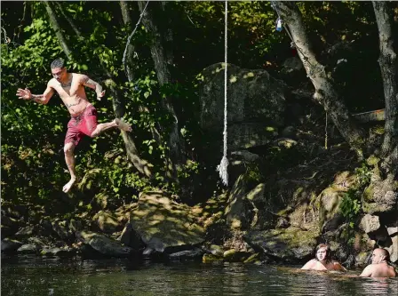  ?? SEAN D. ELLIOT/THE DAY ?? Jose Santiago, of Norwich, goes airborne Monday after launching himself from a rope swing as Ryan Flanders, of Hebron, and his nephew Chad Chaput Jr., 12, of Windham, watch from the edge of the Shetucket River in the Baltic section of Sprague.