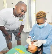  ??  ?? Member of Parliament for South East St Andrew Julian Robinson, observes as dental hygienist Teka Lingard Wolf, a final-year student at the UTech School of Dentistry, cleans the teeth of Karrene Hall.