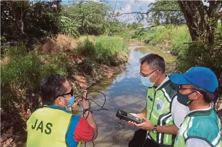  ?? PIC BY ZAIN AHMED ?? Johor Department of Environmen­t director Dr Famey Yusoff (centre) and his officers conducting quality tests at Sungai Kim Kim in Pasir Gudang on Monday.