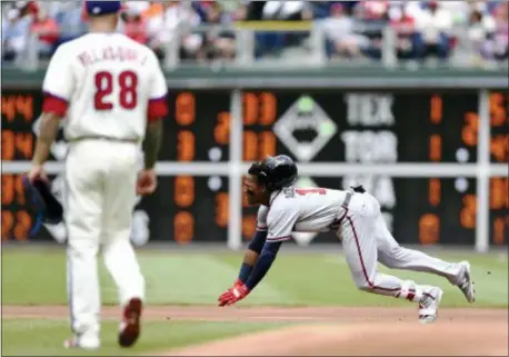  ?? MICHAEL PEREZ — THE ASSOCIATED PRESS ?? Atlanta’s Ronald Acuna Jr., right, dives into second base after a the Phillies Sunday in Philadelph­ia. double to right field in the first inning of a game against