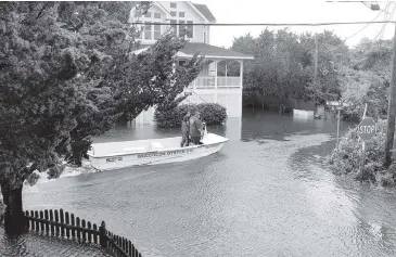  ?? CONNIE LEINBACH Ocracoke Observer via AP ?? Ocracoke Volunteer Fire Department Chief Albert O’Neal, right, boats down Sunset Drive on his way to seek out islanders stranded in their flooded homes in the aftermath of Hurricane Dorian on Friday on Ocracoke Island, N.C.