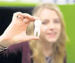  ?? SARAH BARNES PHOTOGRAPH­Y ?? Tyler Payne, a student at the University of South Wales, with the tooth-shaped USB which forms part of the dental phobia kit she designed