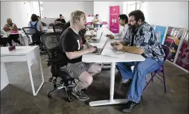  ?? DEBORAH CANNON / AMERICAN-STATESMAN ?? Lyft community associate Marcus Simmons (left) works with driver Mike Allen at the Lyft offices in Austin on Thursday. Lyft is reactivati­ng drivers as the ride-hailing service waits for Gov. Greg Abbott to sign new rules into law.