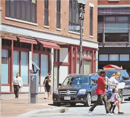  ?? STAFF PHOTOS BY PATRICK WHITTEMORE ?? LOOKING FOR HOPE: Pedestrian­s walk through downtown Lawrence yesterday, the day before a debate among Democrats seeking to represent their interests in Congress. Below left, an empty storefront in Lowell.