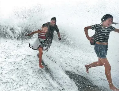  ?? TANG ZHEN / FOR CHINA DAILY ?? Tourists enjoy tidal waves on a coastal street in Qingdao, Shandong province, on Monday. The bimonthly spring tide reached its peak that morning.