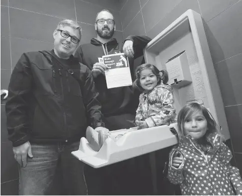  ?? CRAIG GLOVER / POSTMEDIA NEWS ?? Brett Roberts, left, and Jeremy Mccall, with Roberts’ daughters Abby, 2, and Miya, 3, show the new baby changing table in the men’s washroom at Dolcetto restaurant in London, Ont., on Thursday. The men are members of Dad Club, which is asking other establishm­ents to follow suit.