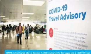  ?? — AFP ?? NEWARK: In this file photo taken on November 21, 2020 travelers wait for their luggage next to a COVID-19 travel advisory at Newark Internatio­nal Airport in Newark, New Jersey.