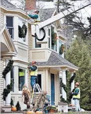  ?? ROBERT F. BUKATY/AP ?? Exterior holiday decorating services will fasten lights to your home and trees, hang wreaths, place rooftop and yard decor, and more. Hiring a pro can save you hassle.