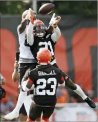  ?? TONY DEJAK — THE ASSOCIATED PRESS ?? Cleveland Browns defensive back Denzel Ward, center, grabs a pass under pressure from wide receiver Jarvis Landry, top, during an NFL football training camp, Thursday in Berea, Ohio.