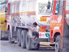  ?? — Reuters ?? A driver reads a newspaper as he sits on a spare tyre attached to a parked oil tanker at a truck terminal in Mumbai, India.