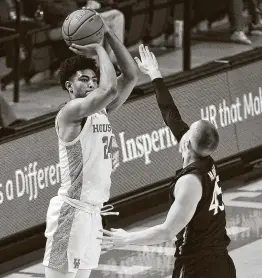  ?? Eric Christian Smith / Associated Press ?? UH’s Quentin Grimes shoots a 3-pointer as Cincinnati’s Mason Madsen defends during the second half Sunday. Grimes posted 20 points and eight rebounds.