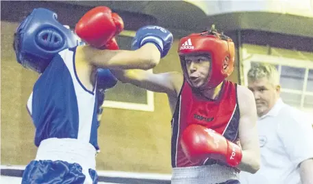  ?? PHOTOS BY BOB TYMCZYSZYN/POSTMEDIA NETWORK ?? R.J. Clarke from the St. Catharines Boxing Club, in red, throws a punch at Max Tomies from Bramalea during their 48kg bout at the McGibbon Gloves boxing match Friday at the Optimist Hall in St. Catharines.