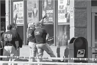  ?? AFP-Yonhap ?? FBI agents look at bullet impacts in a Tops Grocery store in Buffalo, N.Y., May 15, the day after a gunman shot dead 10 people.