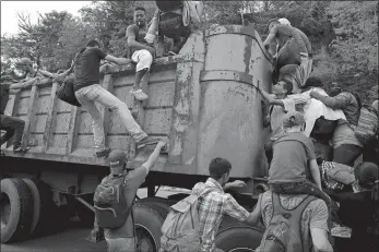  ?? MOISES CASTILLO/AP PHOTO ?? Honduran migrants bound to the U.S border climb into the bed of a truck in Zacapa, Guatemala, on Wednesday. The group of some 3,000 Honduran migrants hit the road in Guatemala again Thursday, hoping to reach the United States despite President Donald Trump’s threat to cut off aid to Central American countries that don’t stop them.