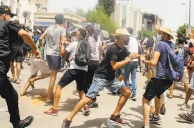  ?? Hassene Dridi / Associated Press ?? A police officer scuffles with demonstrat­ors in Tunis. Security forces were out in force in the nation that unleashed the Arab Spring uprisings a decade ago.