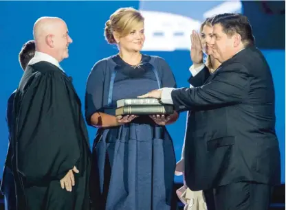  ?? TED SCHURTER/THE STATE JOURNAL-REGISTER VIA AP ?? J.B. Pritzker takes the oath of office from Judge James Snyder as his wife, M.K., looks on during the Illinois inaugural ceremony Monday at the Bank of Springfiel­d Center.