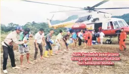  ??  ?? AGIH: Penduduk bekerjasam­a mengangkat bekalan makanan dari helikopter bomba.