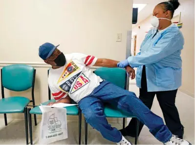  ?? The Associated Press ?? ■ In this Wednesday file photo, Wilbert Marshall, 71, left, pretends to be scared of receiving the COVID-19 vaccine from a nurse at the Aaron E. Henry Community Health Service Center in Clarksdale, Miss. Marshall, who was among a group of seniors from the Rev. S.L.A. Jones Activity Center for the Elderly who received their vaccinatio­ns, said he wanted the vaccinatio­n in order to stay safe and be able to visit with family without the constant fear of the virus.