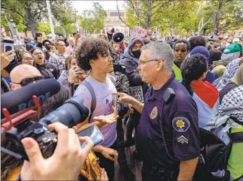  ?? A PUBLIC SAFETY Photograph­s by Brian van der Brug Los Angeles Times ?? officer confronts a demonstrat­or at USC, where protesters chanted, “We will not stop!”