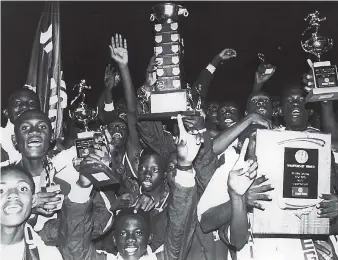  ??  ?? Athletes and supporters of Jamaica College celebrate after the school had retained the Mortimer Geddes Trophy (centre) at the Victoria Mutual Building Society-sponsored Boys’ Championsh­ips at the National Stadium in 1995.