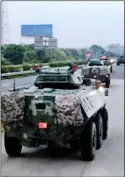  ??  ?? A convoy of armoured troop carriers move towards the border between mainland China and Hong Kong yesterday, while, right, travellers pick their way through pro-democracy protesters at the airport
