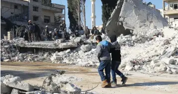  ??  ?? BOYS WALK PAST a site hit by air strikes in the rebel-held city of Idlib yesterday.