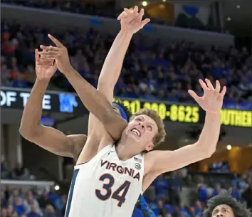  ?? Brandon Dill/Associated Press ?? Virginia’s Jacob Groves, right, vies for position with a Memphis player in a matchup of Top 25 teams Tuesday night in Memphis, Tenn. No. 23 Memphis defeated No. 22 Virginia, 77-54.