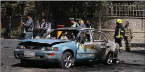  ?? AP ?? Afghan security forces stand guard near a car charred in an explosion Friday near the gates of Kabul University.