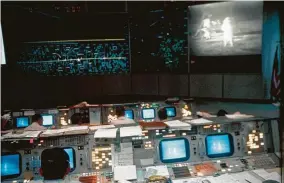  ?? NASA ?? Flight controller­s inside Mission Control monitor Armstrong and Aldrin as they walk on the moon during the Apollo 11 mission on July 20, 1969.