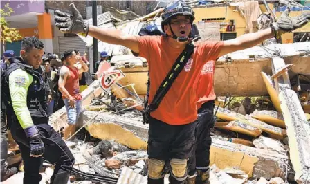  ?? JORGE SANCHEZ AP ?? A rescue worker shouts from the debris of a home that collapsed when an earthquake shook Machala, Ecuador, on Saturday.