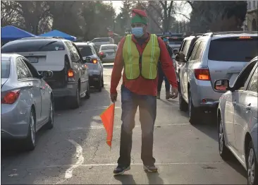  ?? PHOTOS BY JUSTIN COUCHOT — ENTERPRISE-RECORD ?? Dan Rodriguez volunteers to help direct traffic at the food giveaway event on Saturday hosted by the Hispanic Resource Council at RUSH Personnel in Chico.