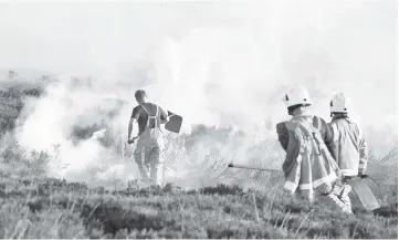  ??  ?? Firefighte­rs tackle a blaze on moorland above Marsden, northwest England. — AFP photo