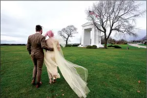  ?? The Associated Press ?? WEDDING: On Sunday, newlyweds Drew MacPherson, a U.S. citizen from Bellingham, Wash., left, and Faith Dancey, a Canadian from White Rock, B.C., stroll through an otherwise deserted portion of the Peace Arch Historical State Park in the U.S. where it abuts Canada in Blaine, Wash.