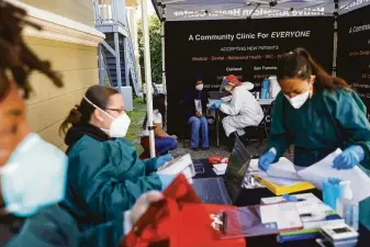  ?? Gabrielle Lurie / The Chronicle ?? Nurse Anna Briggs (center right) chats with a patient before administer­ing the Johnson & Johnson COVID-19 vaccine at the Center for Empowering Refugees in Oakland in March.