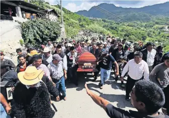  ??  ?? Un grupo de hombres cargaba el féretro del alcalde Domingo López hacia el cementerio del poblado. Mientras un mariachi y una banda acompañaba­n el trayecto, pobladores observaban la procesión desde los techos.