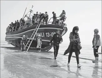  ?? GARETH FULLER / PA VIA ASSOCIATED PRESS ?? People thought to be migrants crossing from France come ashore at Dungeness in southern England on Tuesday after they were picked up by a lifeboat.