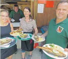  ?? FOTO: HELMUT STROPPEL ?? Beim Fischerfes­t in Gutenstein müssen die Bedienunge­n Janina Gregori, Martina Bosch und Michael Ruhnau Schwerstar­beit leisten, um die Forellen an den Mann und an die Frau zu bringen.