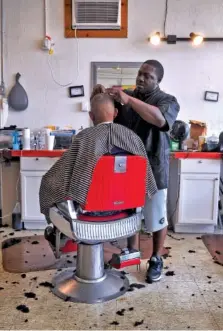  ??  ?? Randolph's Barber Shop barber Davon Ivey cuts Kevin Harris's hair at the Athens Street barber shop in Gainesvill­e.