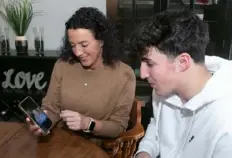  ?? John Colombo/for the Post-Gazette ?? Liz Mancing and her son Kyle, 16, look at a photo of baby Kyle taken after he got out of the ICU.