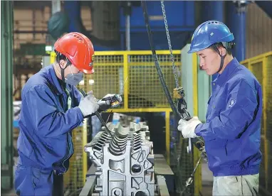  ?? PHOTOS PROVIDED TO CHINA DAILY ?? Technician­s at Weichai Power, a leading heavy truck engines and components manufactur­er at the Weifang Hi-tech Industrial Developmen­t Zone, check measuremen­ts of an engine.