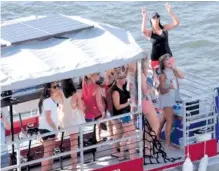  ?? STAFF PHOTO BY TIM BARBER ?? A group of young pass behind the Coca-Cola Stage aboard the Chattanoog­a Cycleboats vessel as Salt N Pepa take the stage during the Riverbend Festival.