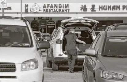  ?? Yi-Chin Lee / Houston Chronicle ?? A man loads groceries into the trunk of his car after shopping at Welcome Food Center on Friday in Houston. Many are avoiding shopping at Jusgo Supermarke­t and Welcome Food Center during the night because of an uptick in robberies.