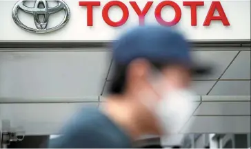  ?? — AP ?? Heat wave: A man walks past a Toyota dealer. The Japanese automaker shut a factory in the provincial capital of Chengdu and will keep operations suspended until Aug 20.