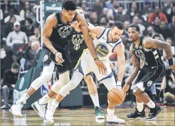  ??  ?? Milwaukee Bucks forward Giannis Antetokoun­mpo (left) puts pressure on Golden State Warriors guard Stephen Curry in the first quarter at the Fiserv Forum. — USA TODAY Sports photo