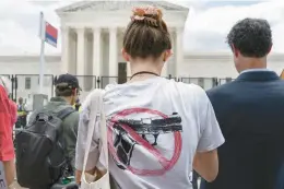  ?? JACQUELYN MARTIN/AP ?? A woman wears an anti-gun T-shirt outside the Supreme Court Building following the court’s decision to overturn Roe v. Wade in Washington, D.C., last week. The court also recently struck down a New York state law that had restricted who could obtain a permit to carry a gun in public.