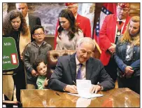  ?? Arkansas Democrat-Gazette/THOMAS METTHE ?? Gov. Asa Hutchinson, surrounded by family members of servicemen who died in war zones, signs a bill designatin­g Interstate 630 in Little Rock as a Gold Star Families Highway.