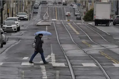  ?? JEFF CHIU — THE ASSOCIATED PRESS FILE ?? A pedestrian carries an umbrella while crossing a street in San Francisco on April 14.