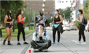  ?? GERALD HERBERT/AP ?? MENCARI JALAN DAMAI: Seorang demonstran bersila di tepi jalan di Loyola Avenue, New Orleans, Selasa (2/6). Foto kiri, peserta aksi bersalaman dengan polisi di Hollywood Boulevard, Los Angeles. Meski ada kericuhan, banyak pula demonstran yang menjalanka­n aksi damai.